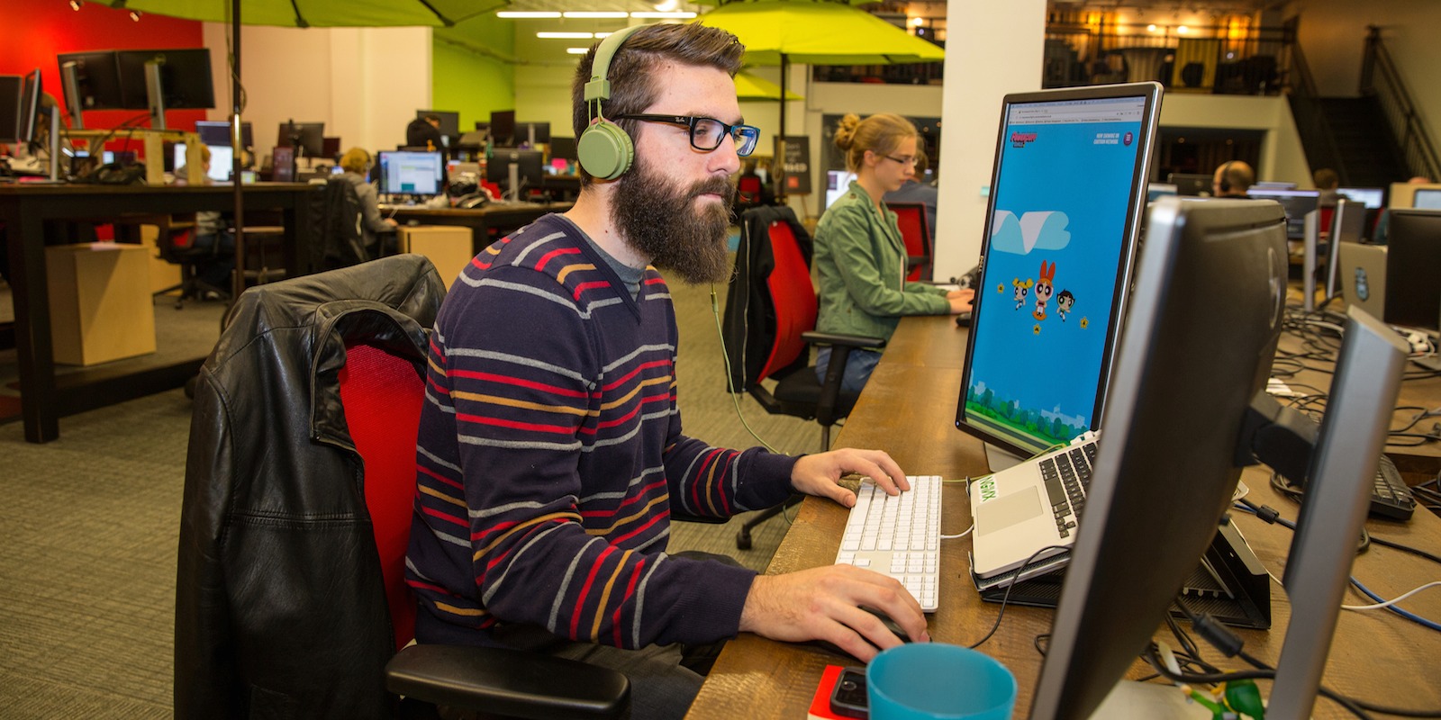 Young man sitting in an open concept office in front of a computer